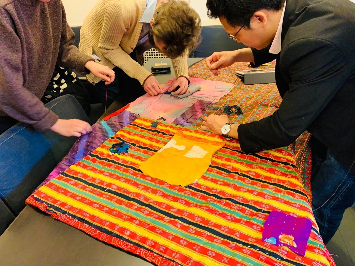 Participants stitching a colourful collective quilt